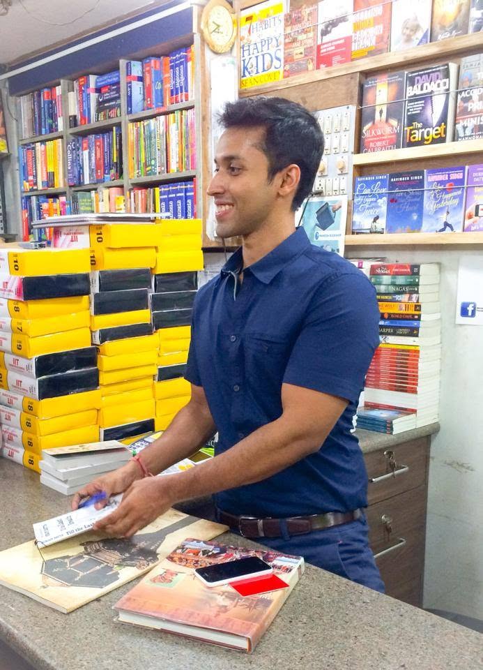 A bookseller arranging books at the Maneesh Book Shop counter