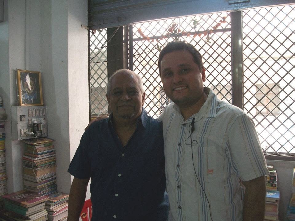 Two people standing together inside Maneesh Book Shop near the window