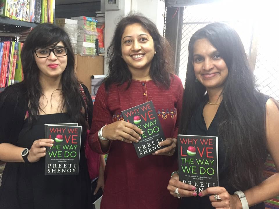 Three women holding copies of Why We Love The Way We Do inside Maneesh Book Shop